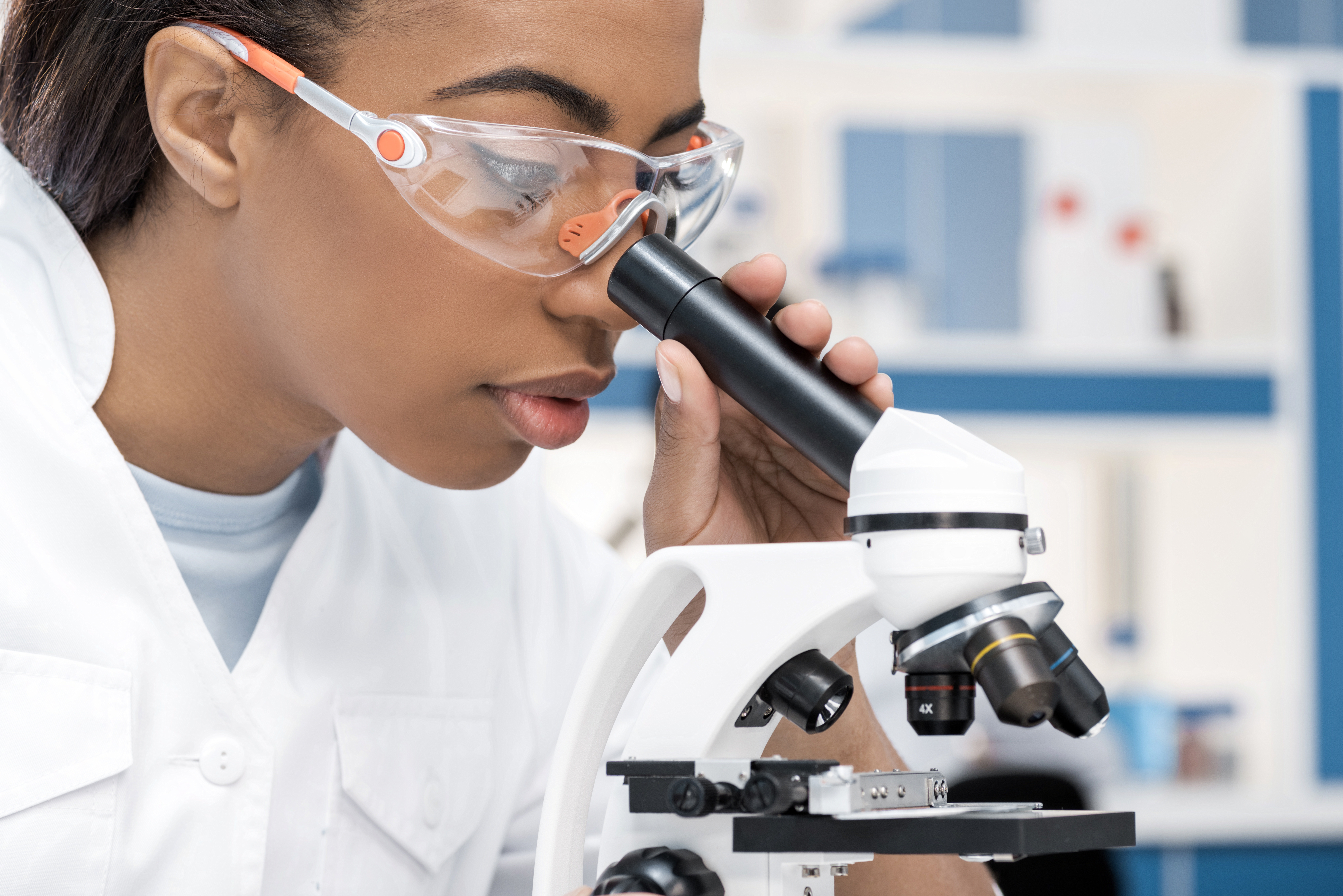 concentrating scientist in lab coat working with microscope in chemical lab