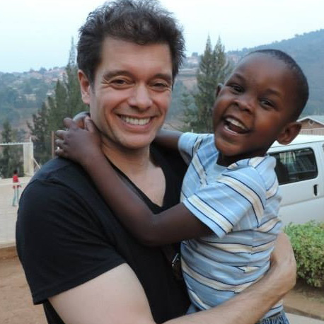 Michael Stromme holding a child, both are smiling widely