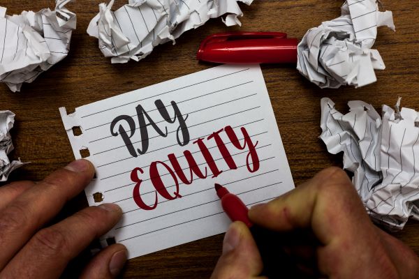 Hand writing Pay Equity on piece of paper
