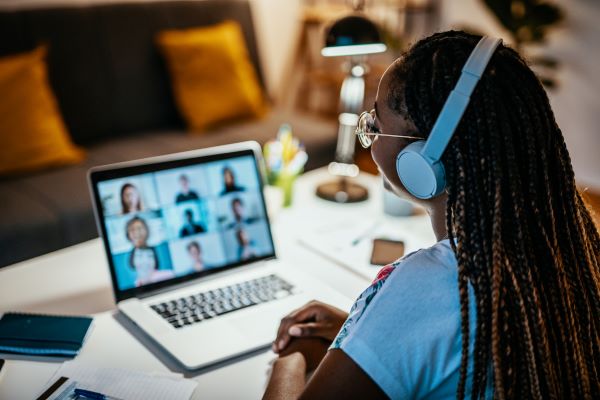 Person looking at laptop, participating in virtual team meeting