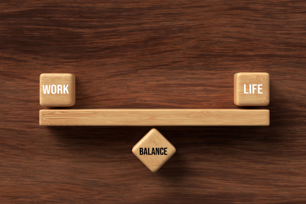 Wooden blocks formed as a seesaw with the words WORK, LIFE and BALANCE on wooden background 