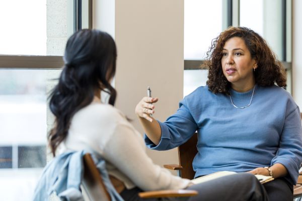 A higher ed professional giving peer feedback to another colleague