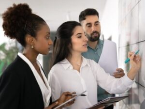 Higher ed colleagues review and discuss data on a whiteboard